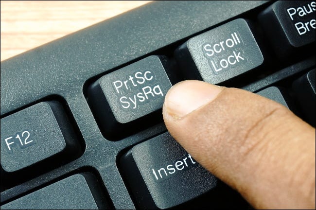 Палец, нажимающий клавишу PrtSc в верхнем ряду клавиатуры ПК