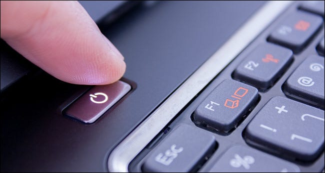 Палец нажимает кнопку питания ноутбука.