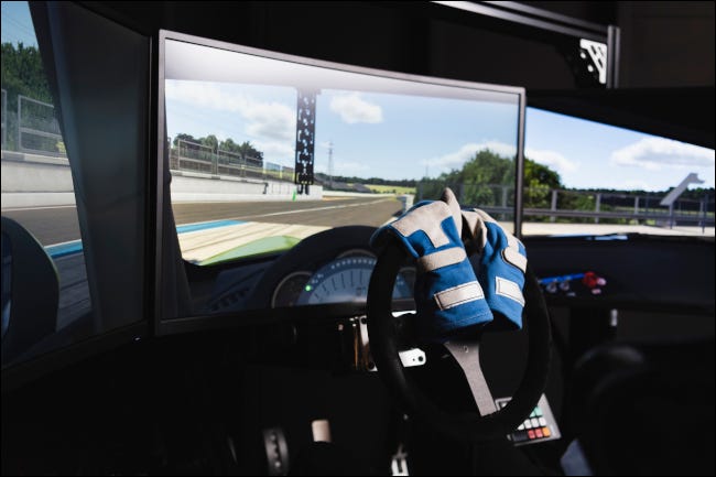 Интерьер установки гоночного симулятора с водительскими перчатками на руле.