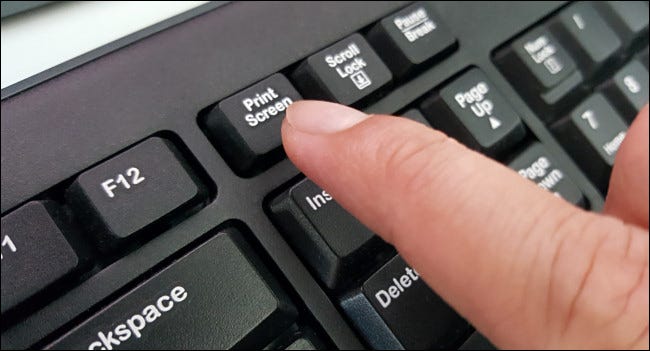 Палец, нажимающий клавишу Print Screen на клавиатуре.